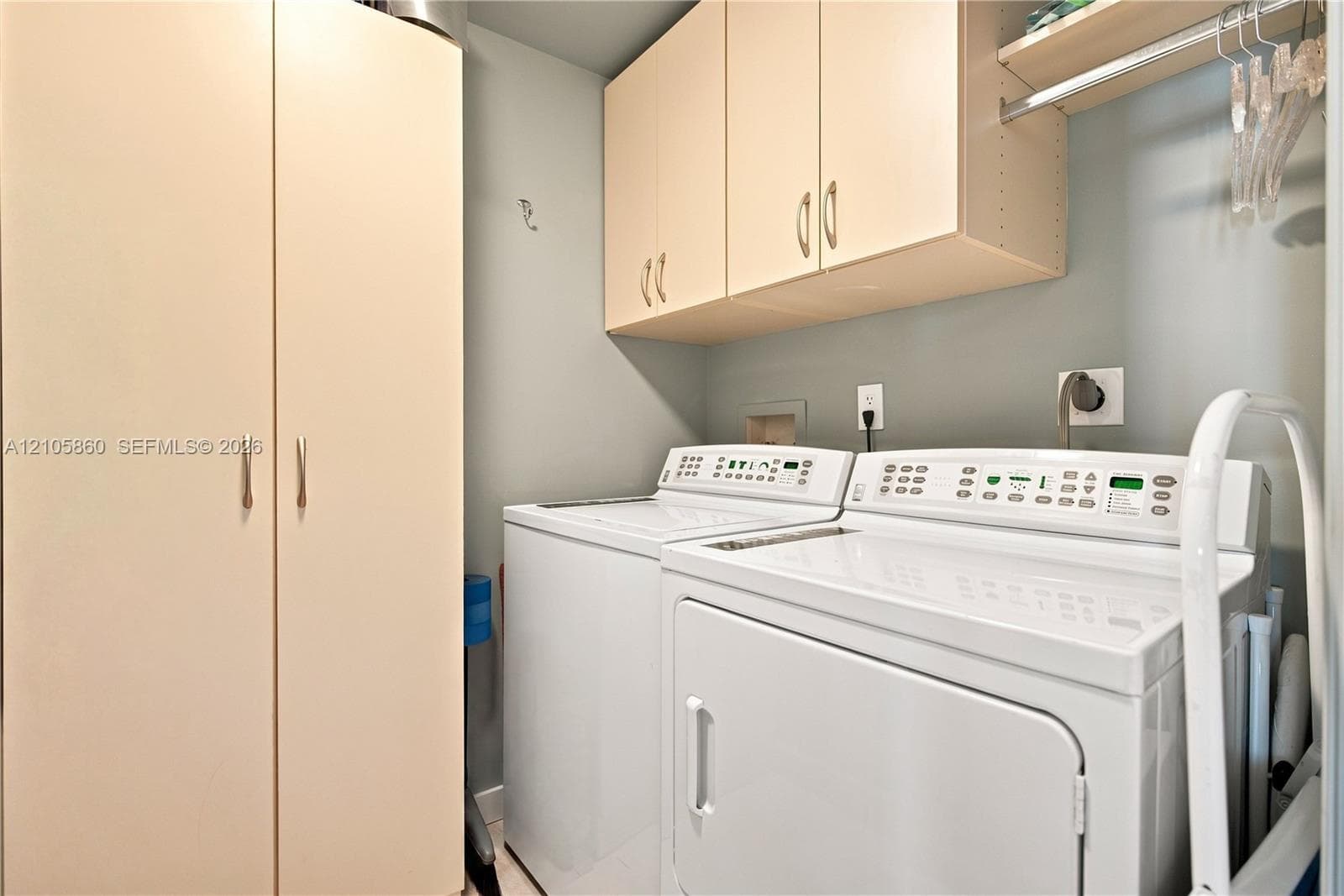 Laundry area featuring full-height pantry-style cabinetry, overhead wall-mounted storage cabinets, and a horizontal hanging rod