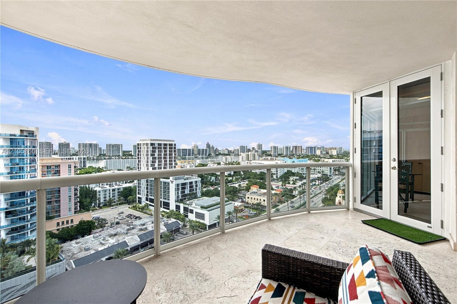 Covered balcony featuring stone-finish flooring, glass-paneled railing, and double-door access
