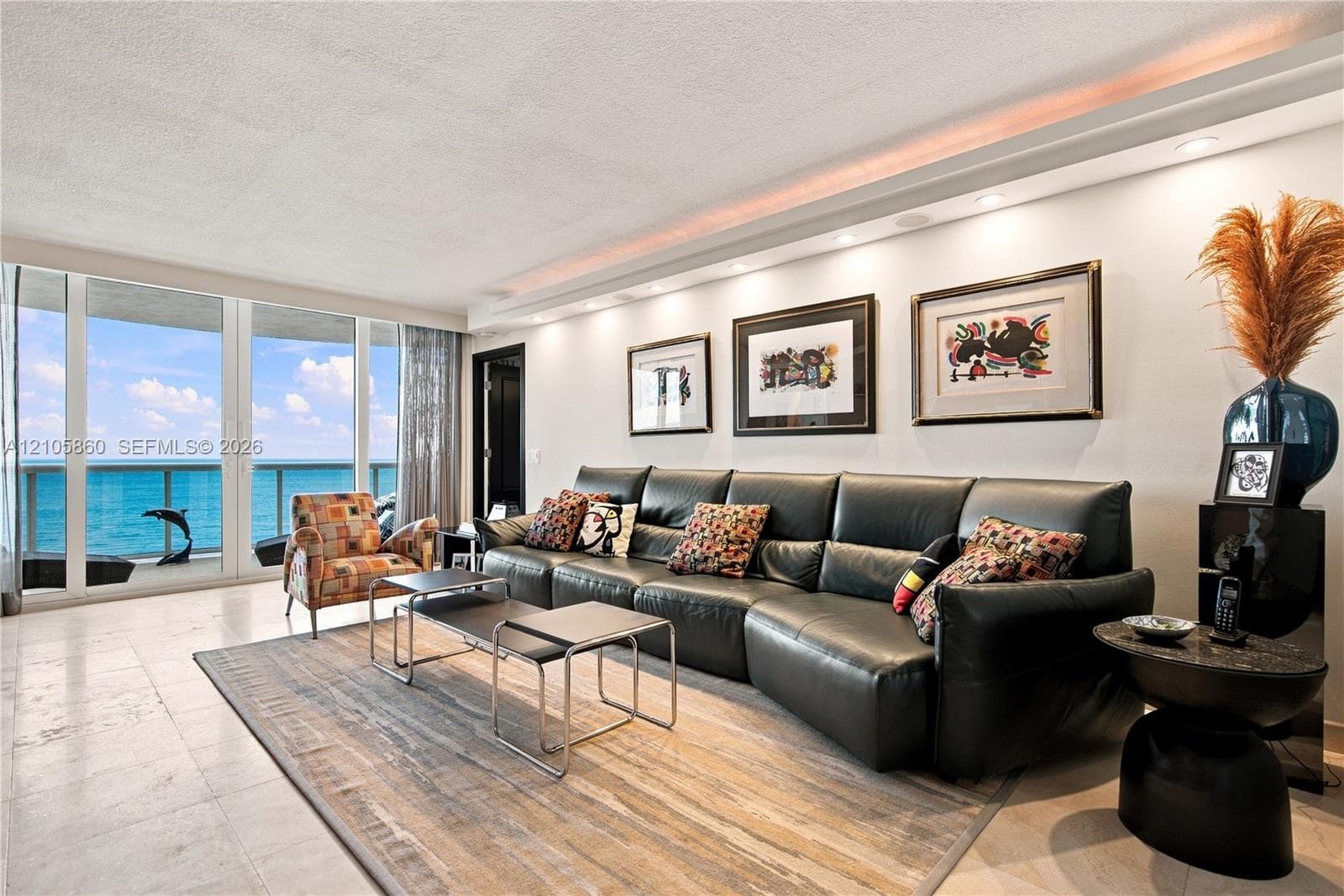 Floor-to-ceiling glass windows, recessed ceiling lighting with crown molding, polished stone flooring, and expansive water frontage