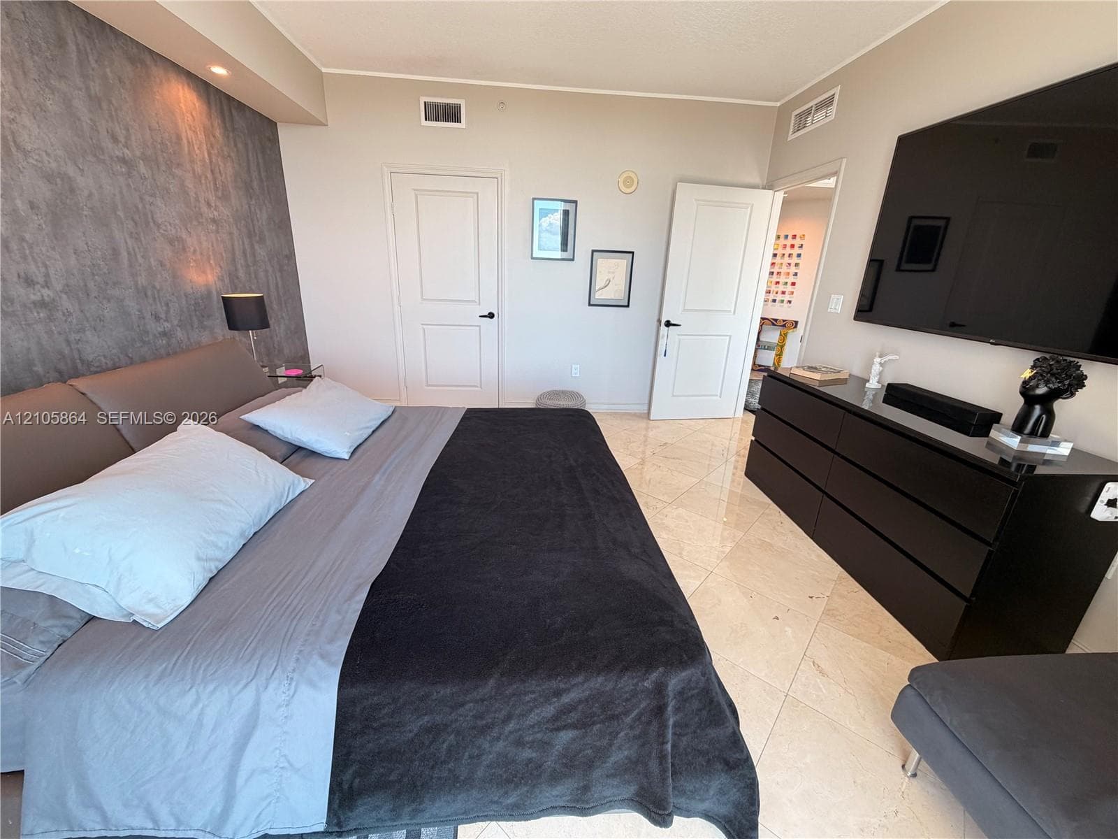 Textured grey feature wall, polished stone-finish flooring, and two-panel interior doors with matte black hardware