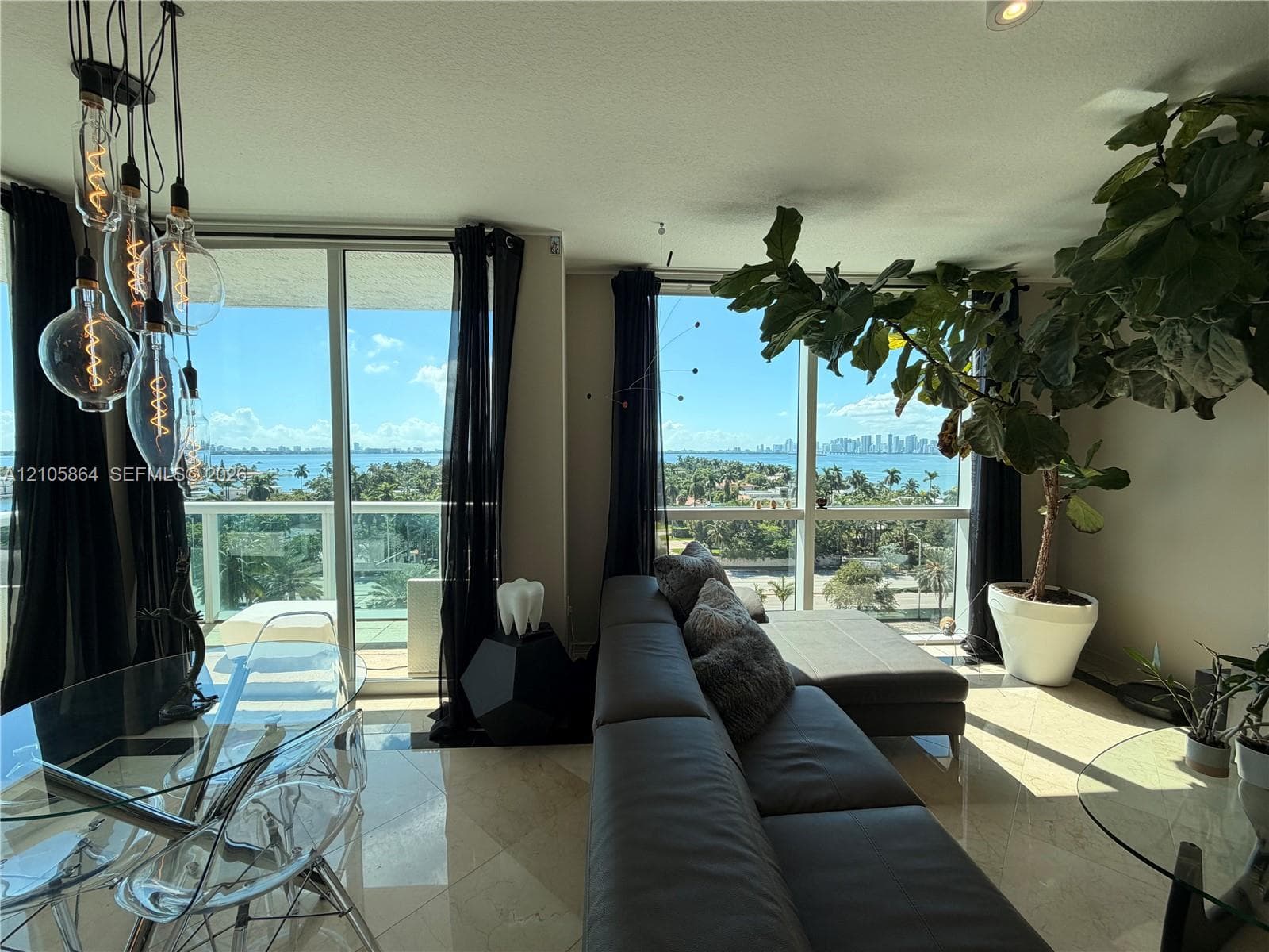 Floor-to-ceiling windows, polished stone flooring, multi-pendant Edison-style lighting, and glass balcony railings
