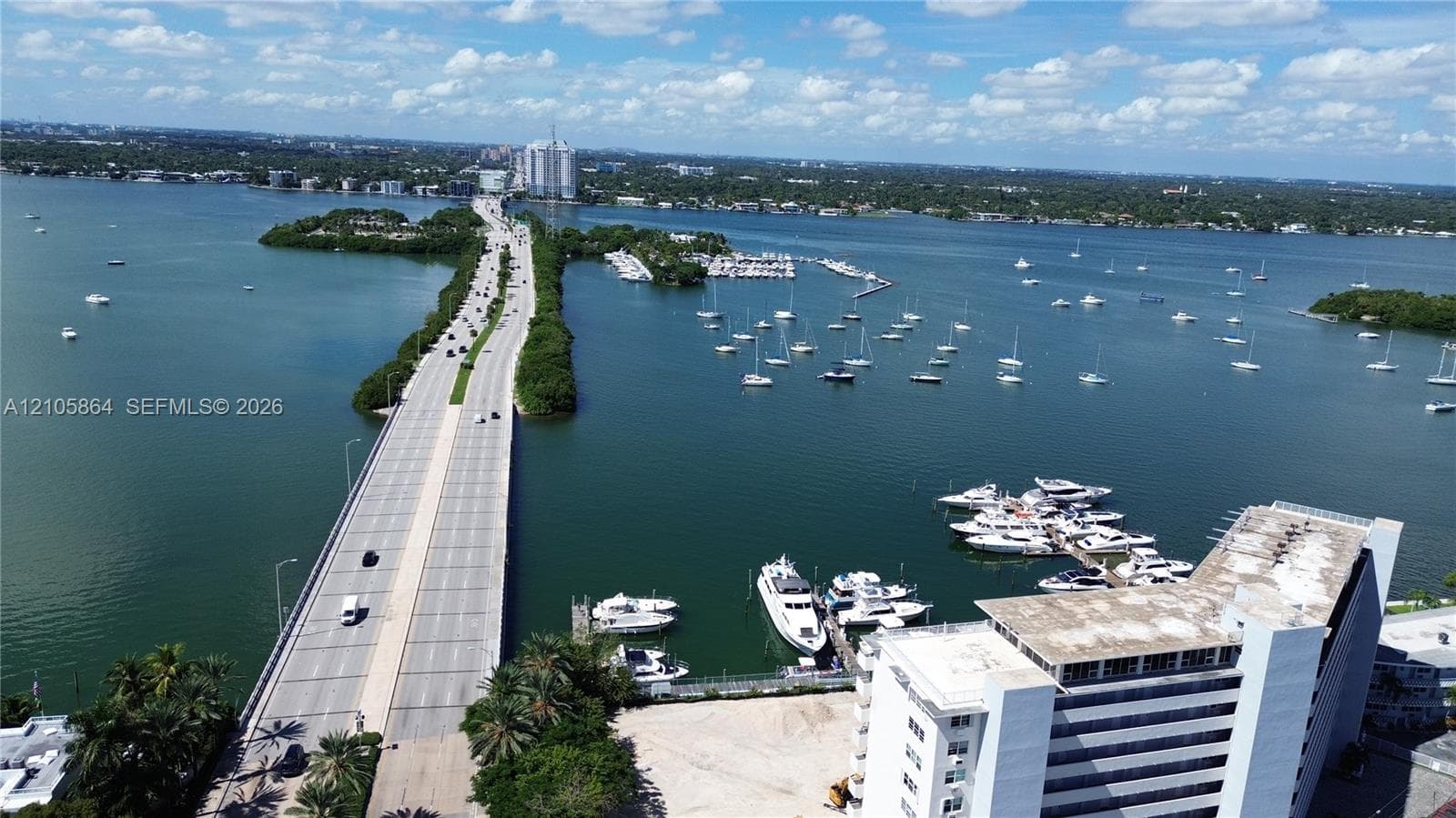 Aerial perspective featuring proximity to the waterfront, a multi-story building, an adjacent bridge, and local boating infrastructure