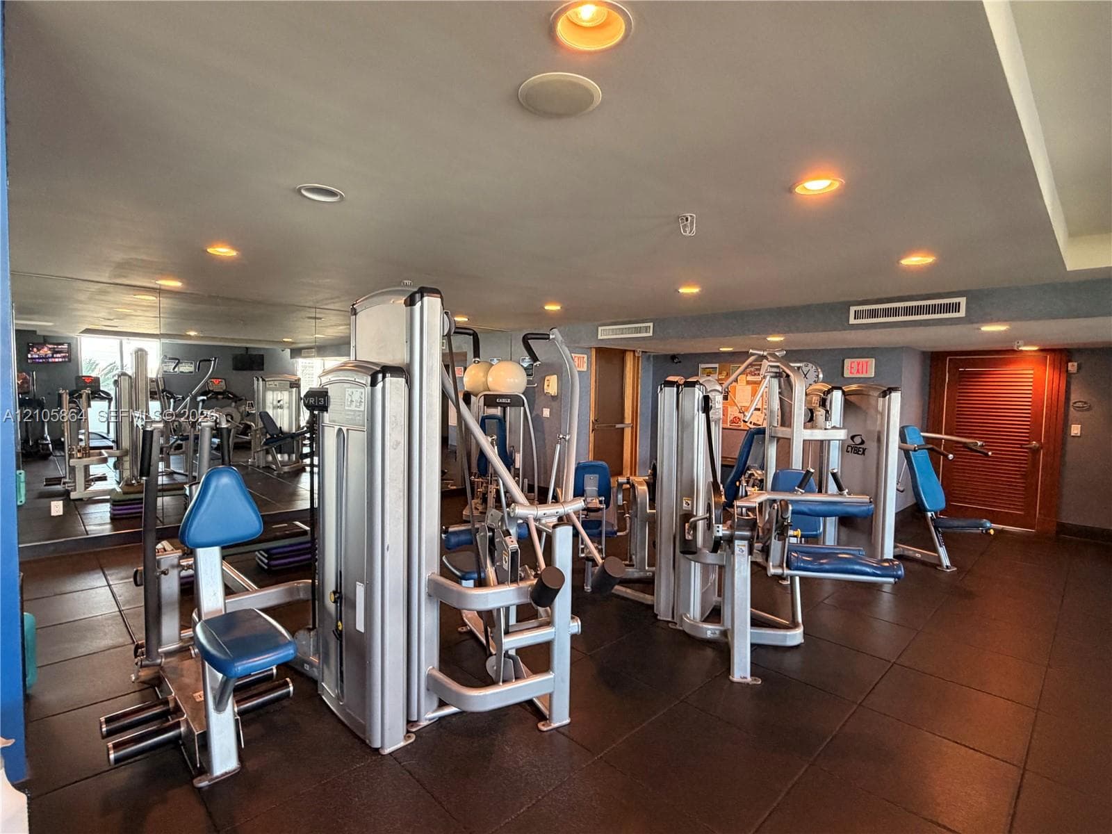 Fitness room featuring rubberized flooring, recessed lighting, mirrored walls, and solid-wood door