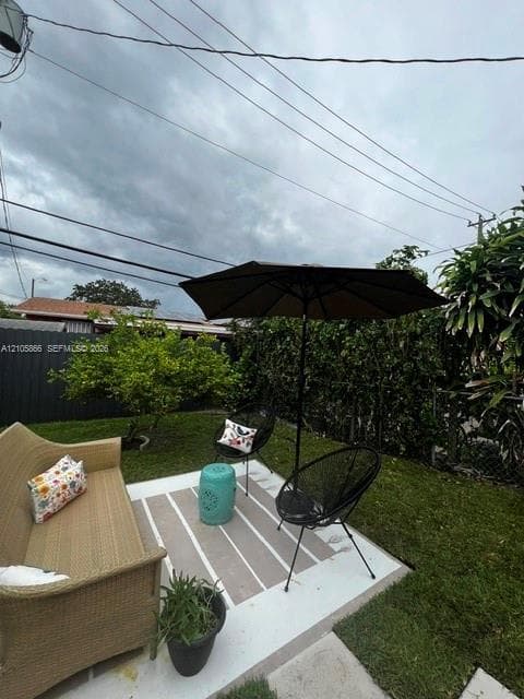 1/1's Backyard featuring a concrete patio, perimeter privacy fencing, and established shrubbery