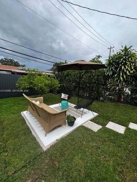 1/1's Backyard featuring a concrete patio, perimeter privacy fencing, and established shrubbery