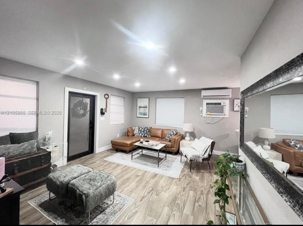 Interior space featuring wood-finish flooring, recessed lighting, wall-mounted air conditioning unit, and a glass-paneled exterior door