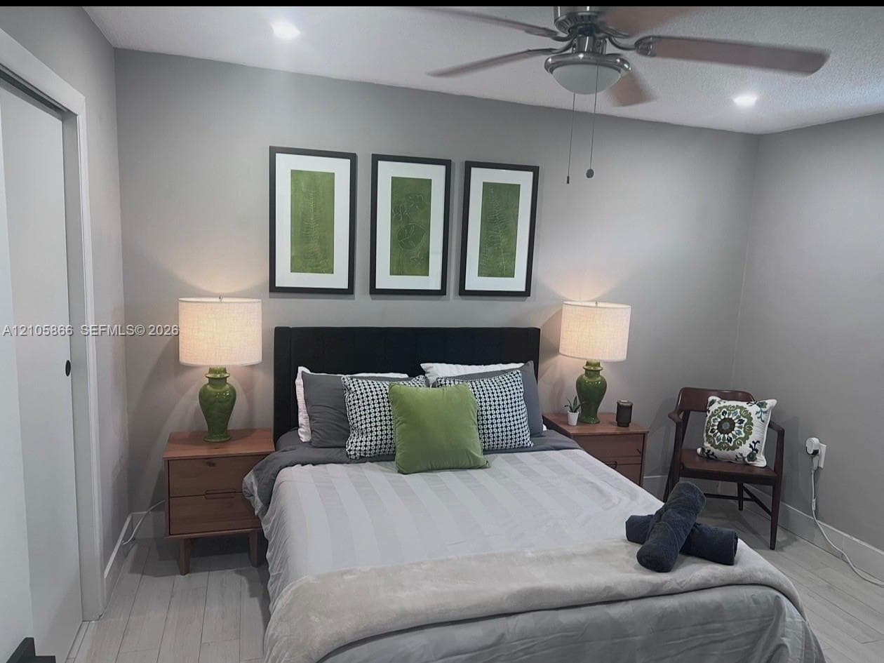 Neutral-toned walls paired with light wood-finish flooring and a ceiling-mounted light fixture with an integrated fan
