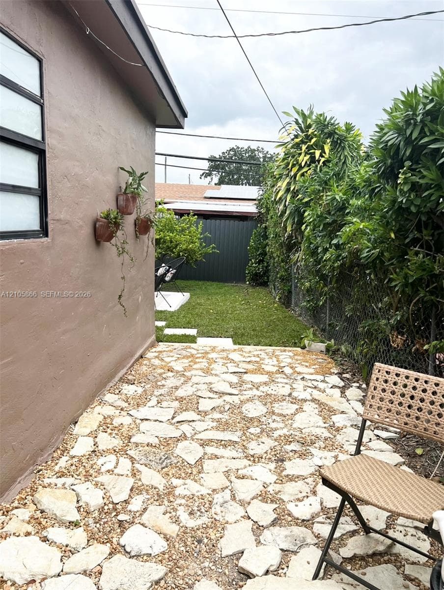 1/1 private walkway to yard featuring a flagstone patio, manicured lawn, and privacy fencing