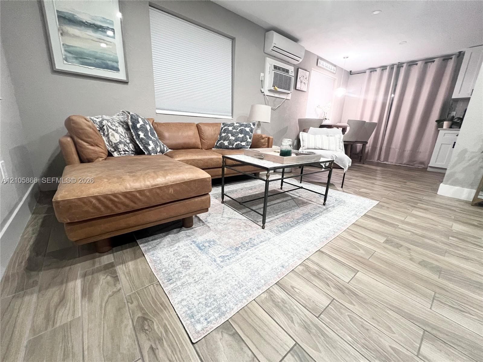 Living area featuring wood-finish tile flooring, recessed lighting, and wall-mounted climate control unit