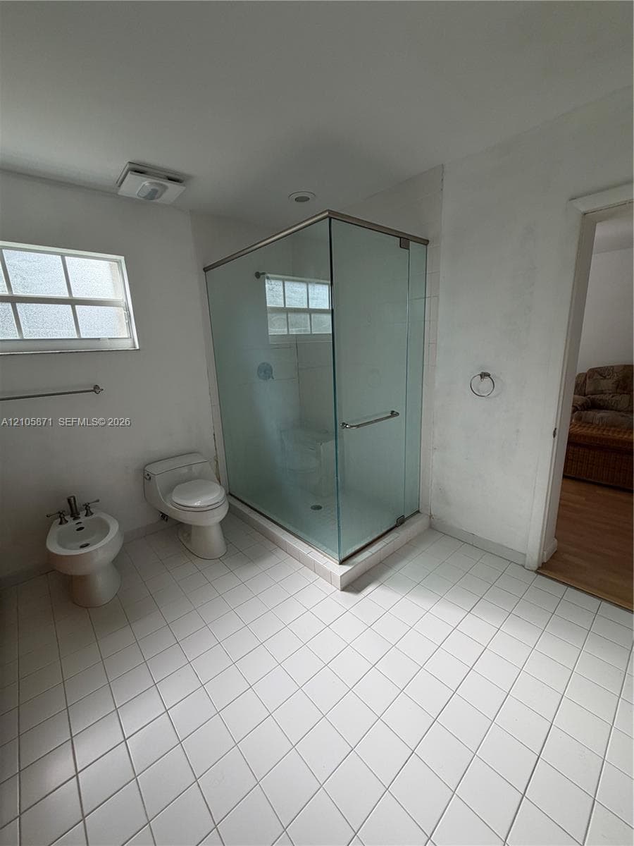 Bathroom featuring a glass-enclosed shower, ceramic tile flooring, bidet, and a single-pane window