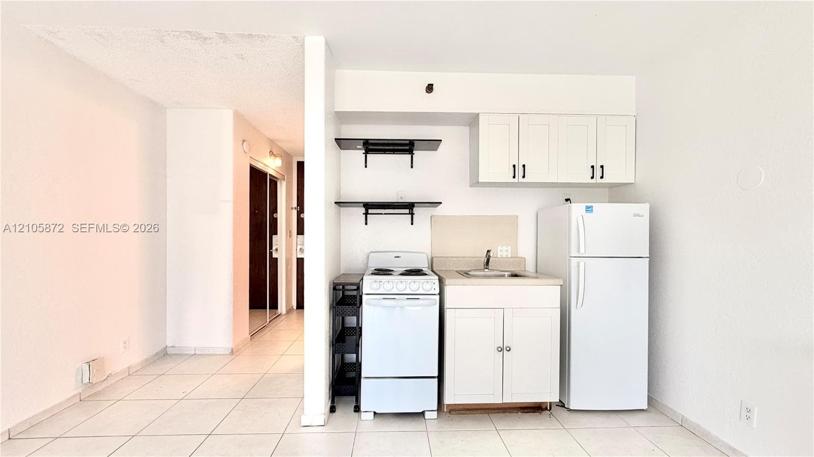 Kitchenette featuring white cabinetry, open shelving, tile flooring, and integrated white appliances
