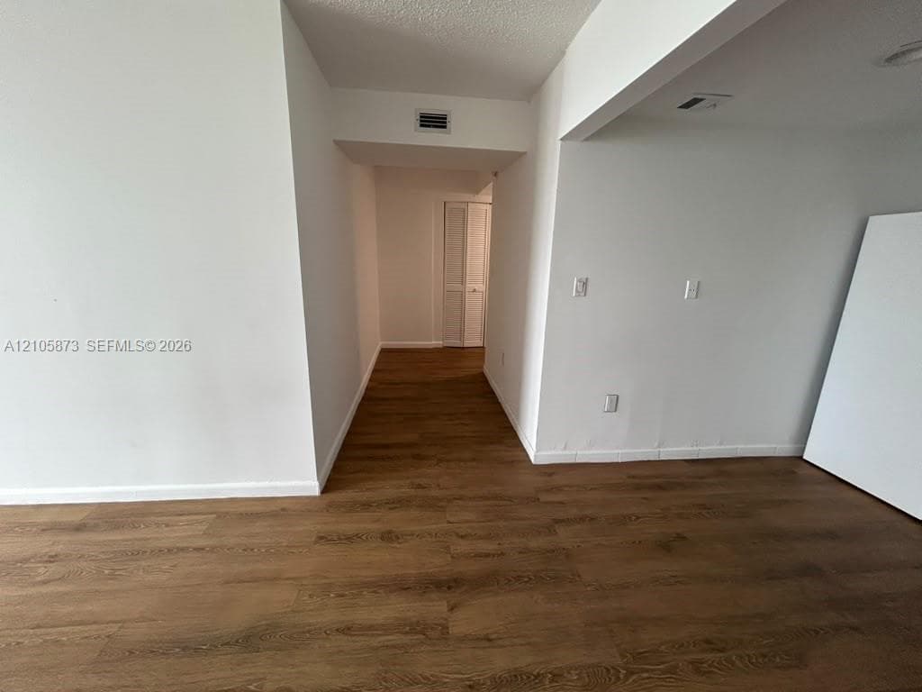 Interior space featuring wood-finish flooring, white wall surfaces, and bi-fold closet doors