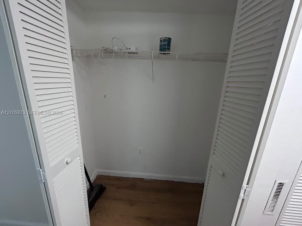 Closet interior featuring double louvered doors, wood-finish flooring, and a wire-rack shelving system