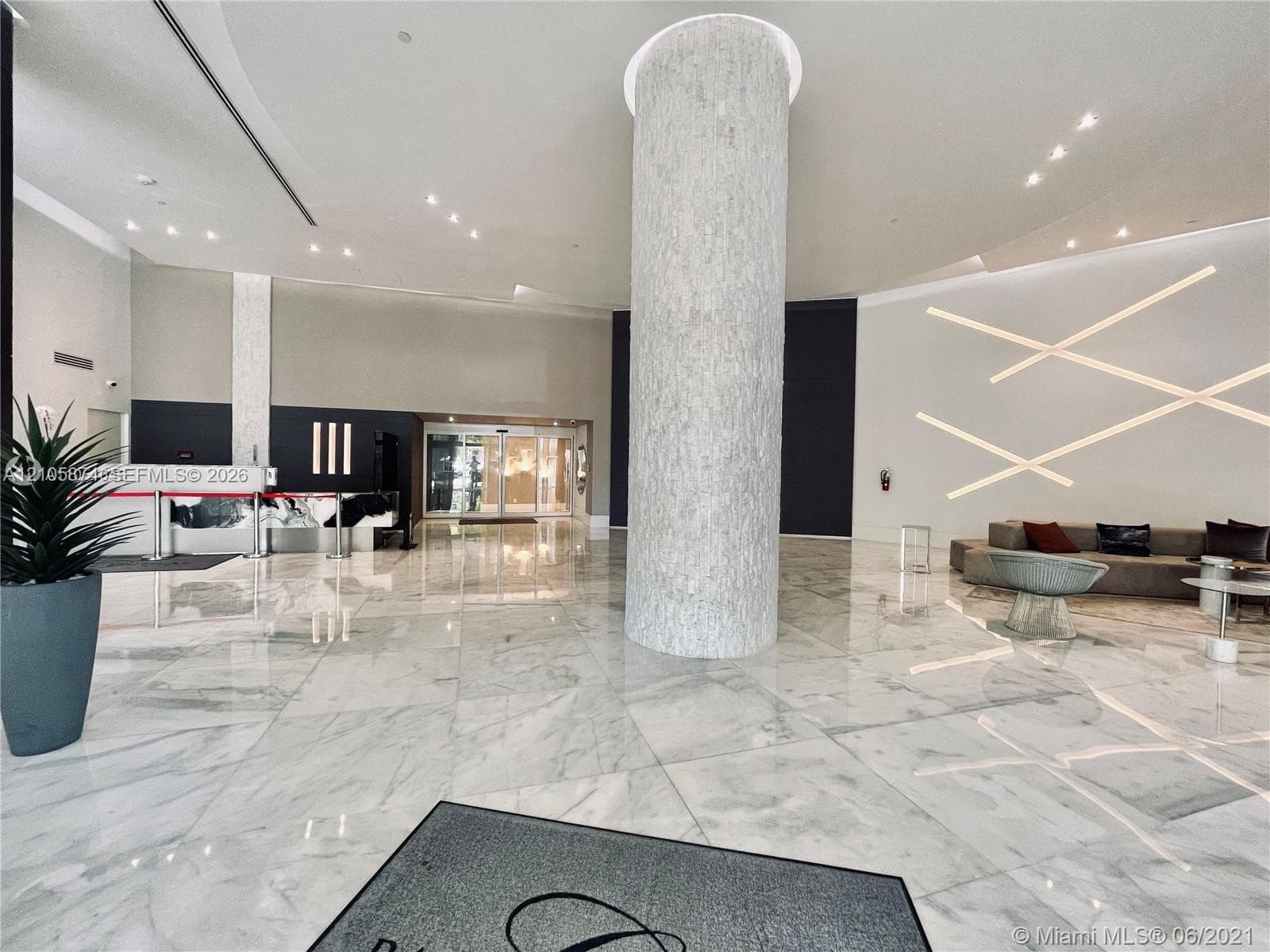 Grand lobby featuring expansive stone tile flooring, a central textured stone-clad pillar, recessed ceiling lighting, and linear wall-mounted accent lighting