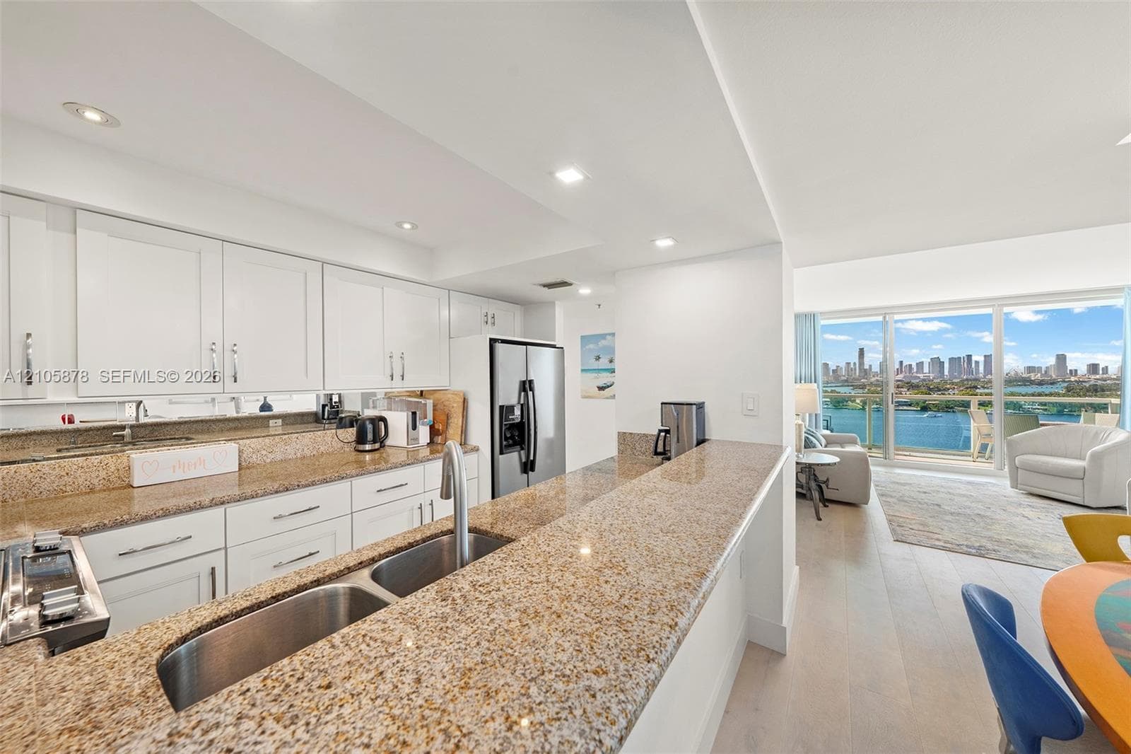 Kitchen featuring white shaker-style cabinetry, stone countertops, stainless steel dual-basin undermount sink, recessed lighting, and wood-finish flooring