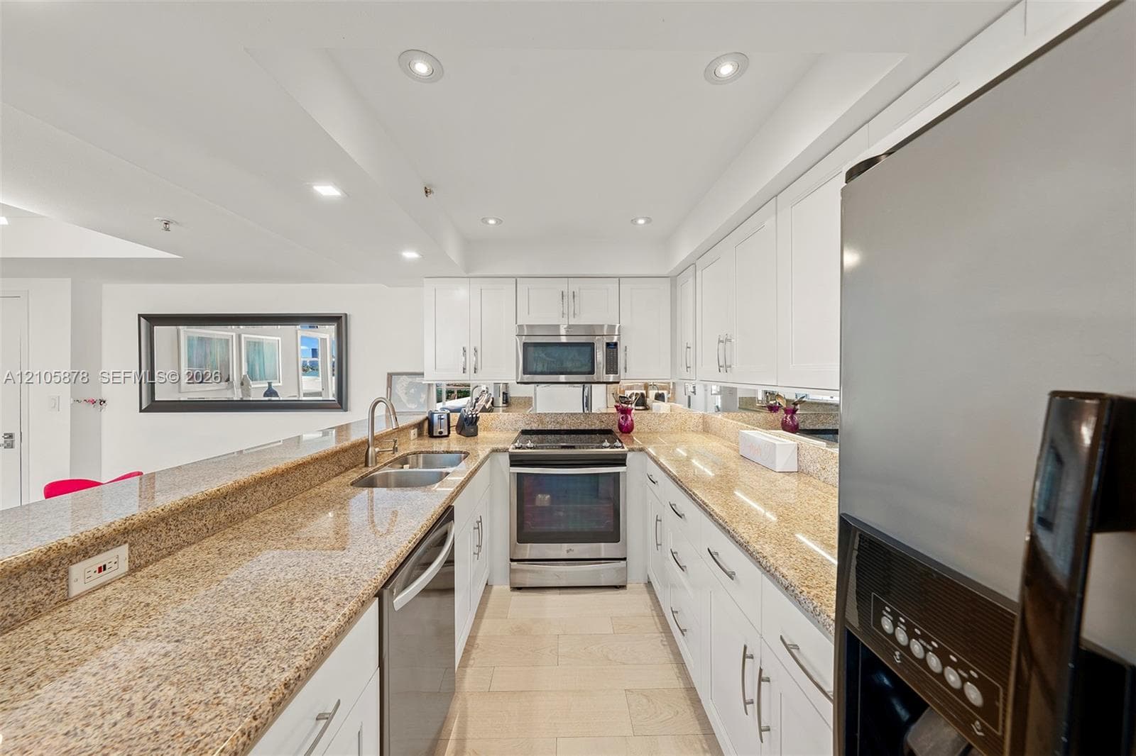 Kitchen featuring white cabinetry, stone countertops, stainless steel appliances, a double-basin sink, and tile flooring
