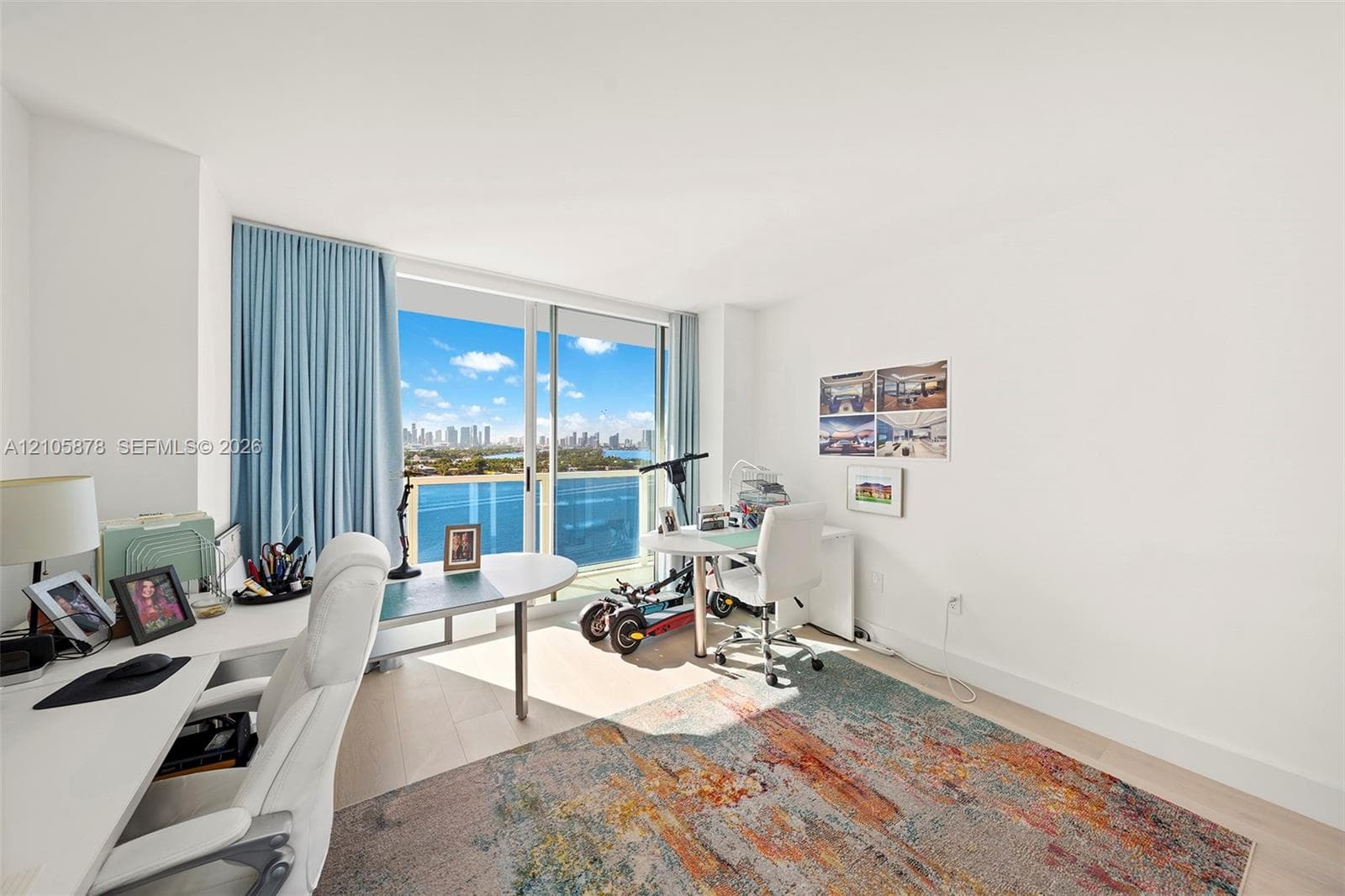 Floor-to-ceiling sliding glass door, light-toned wood-finish flooring, and expansive water and skyline backdrop