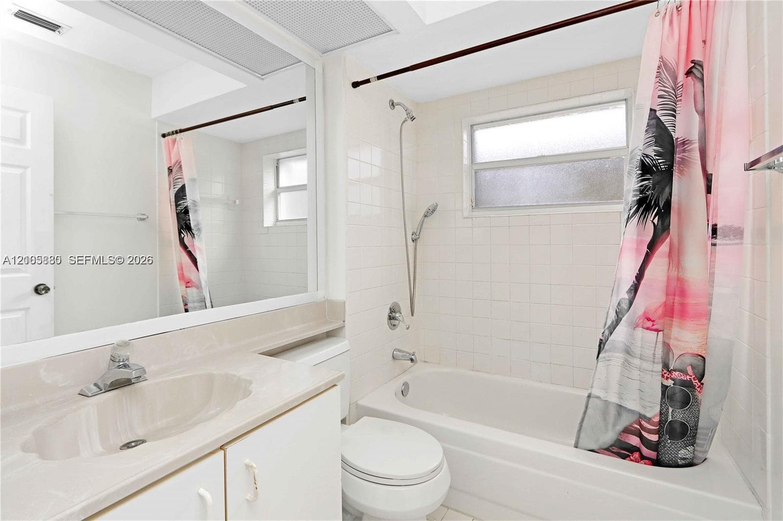 Full-width vanity with an integrated sink, expansive wall-mounted mirror, white ceramic tile shower surround, and a handheld shower fixture