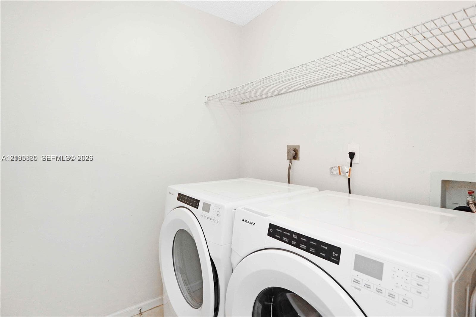 Dedicated laundry area featuring white side-by-side appliances and overhead wire shelving