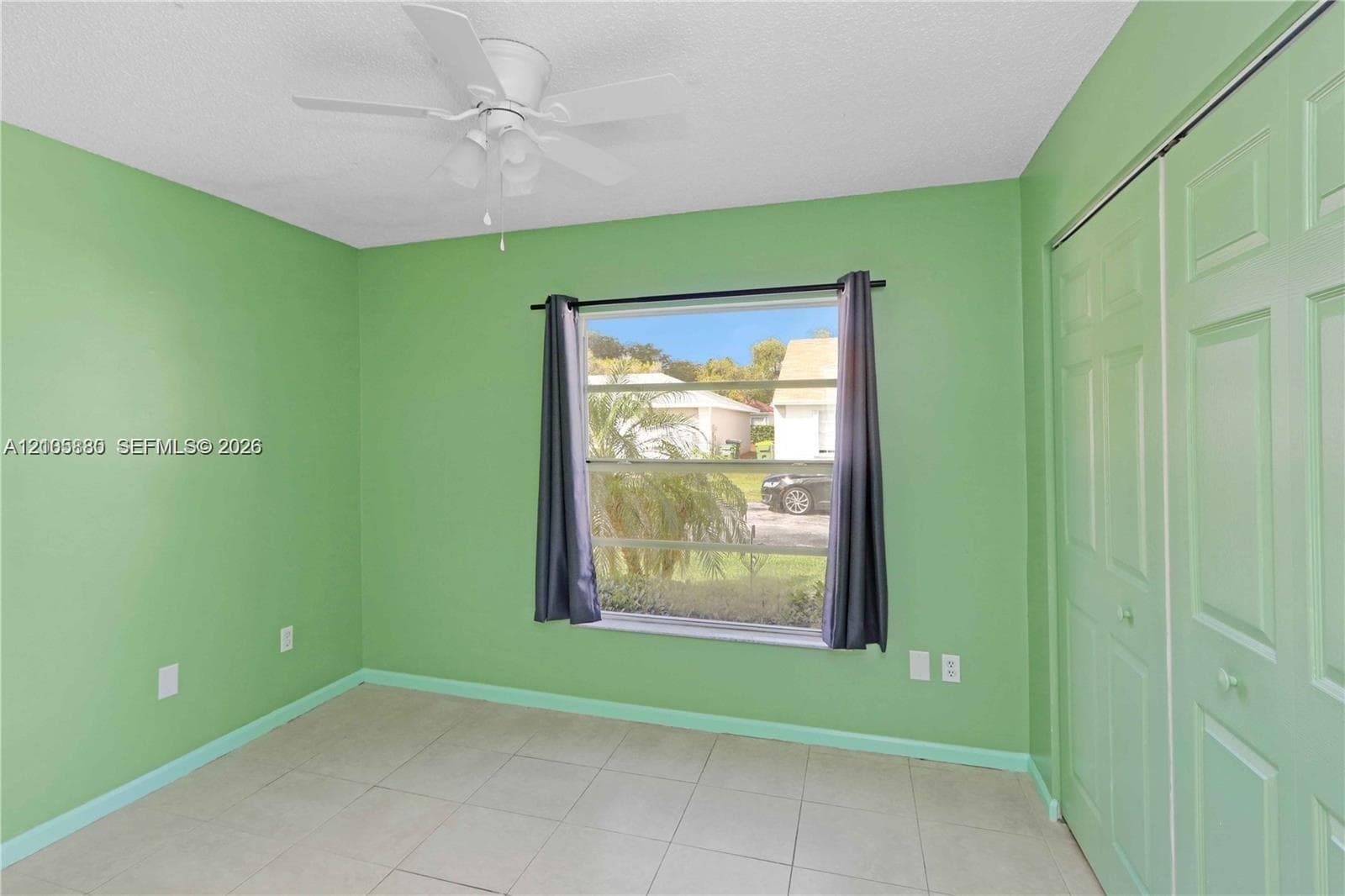 Room featuring tile flooring, a multi-pane window, a ceiling fan with integrated lighting, and a bi-fold closet