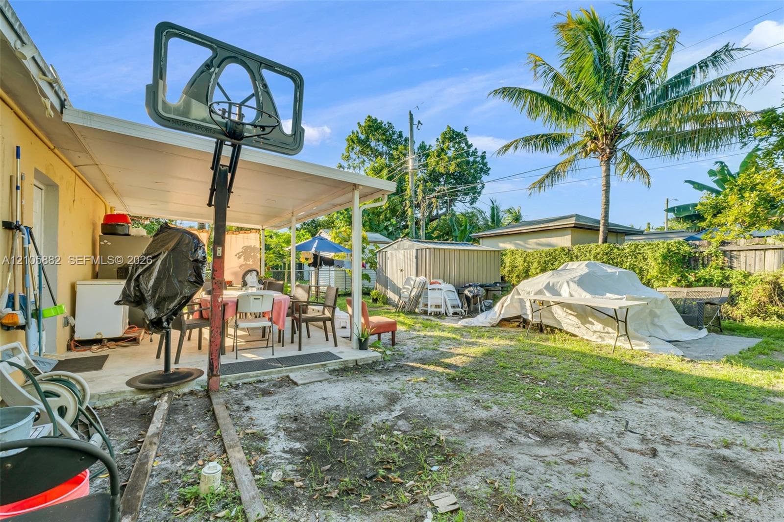 Covered concrete patio with support columns and backyard storage shed