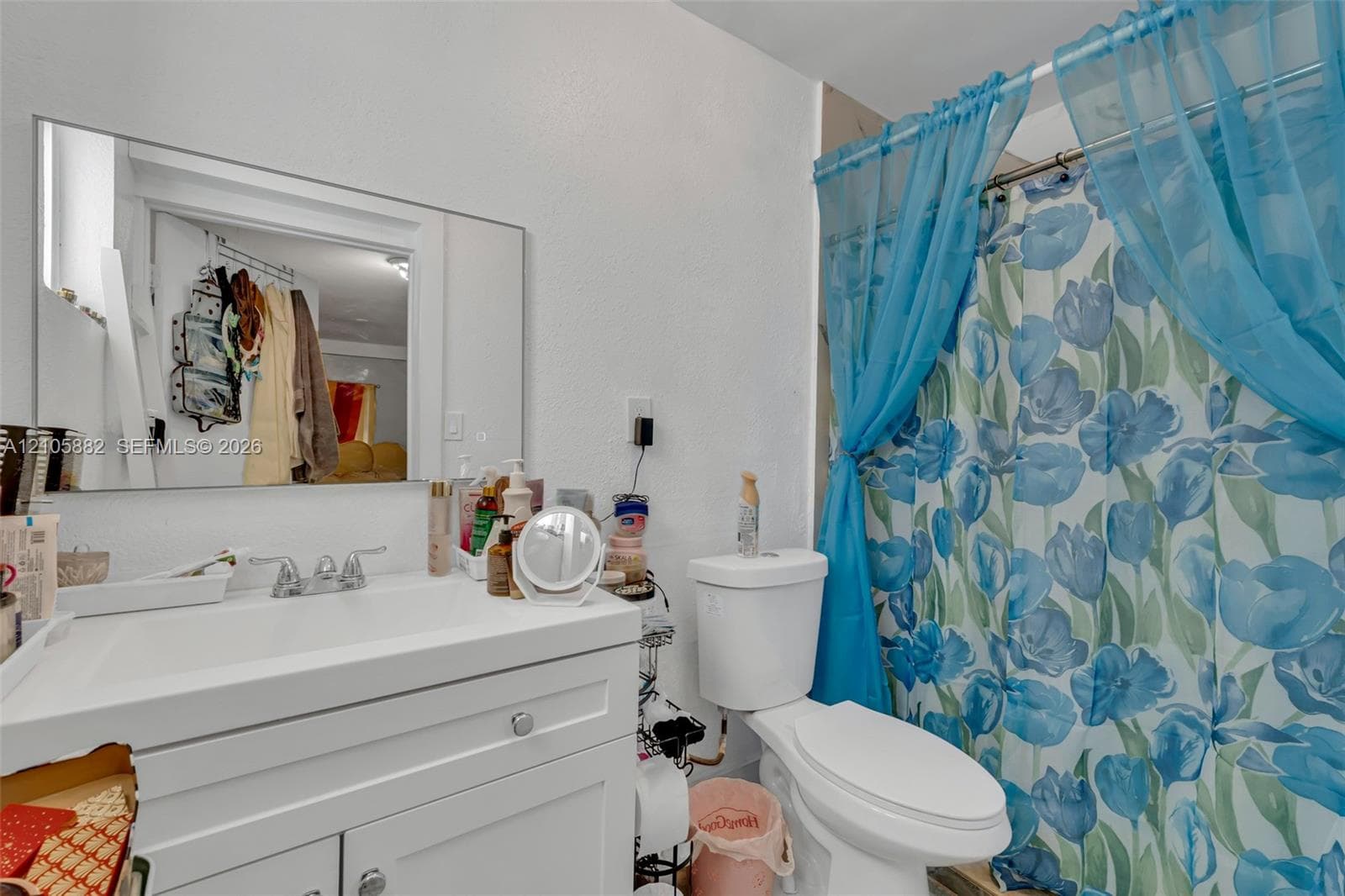 White vanity featuring a rectangular integrated sink, chrome faucet, and storage cabinetry with polished hardware, complemented by a large wall-mounted vanity mirror