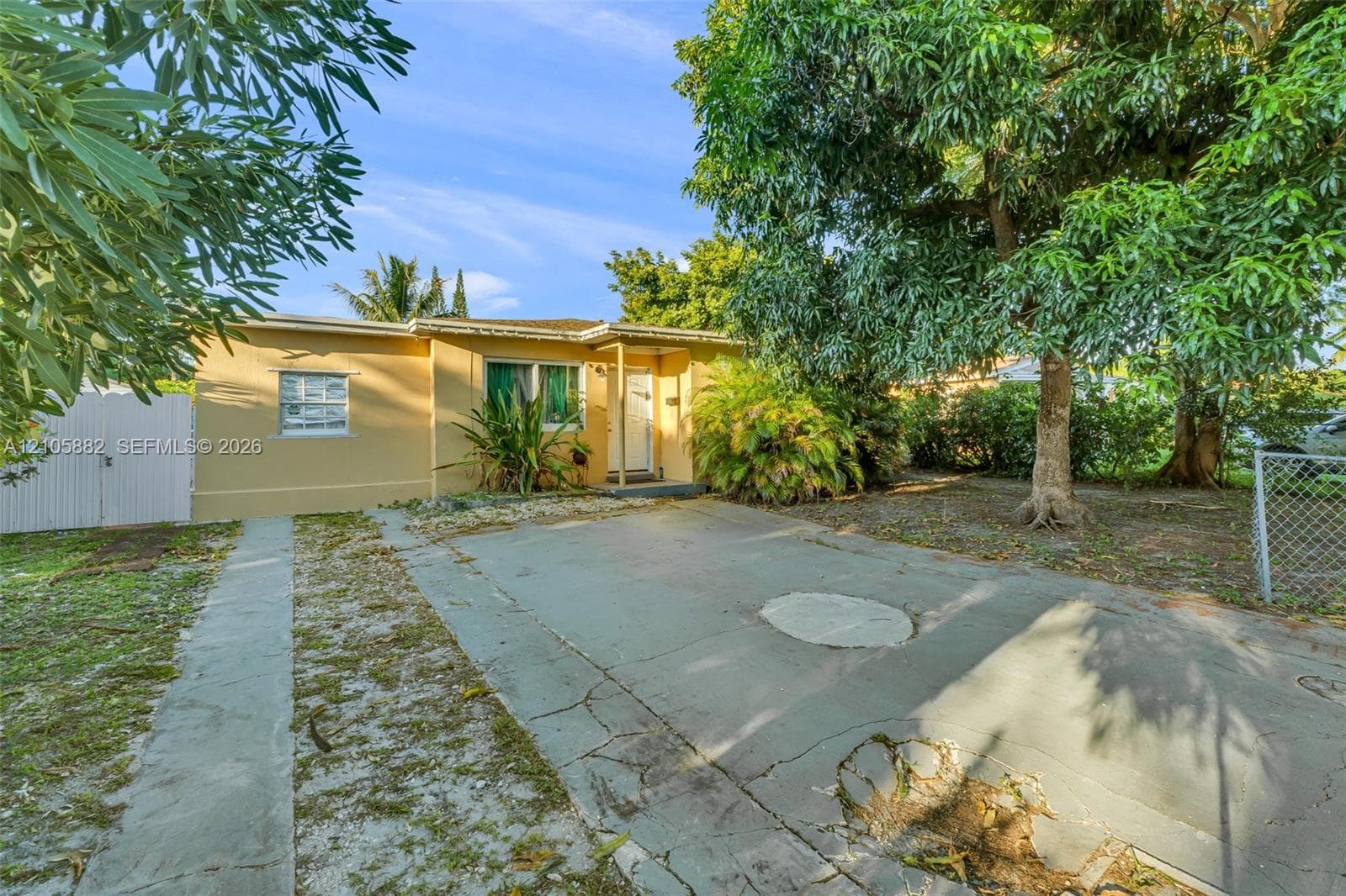 Single-story residence featuring a stucco exterior, concrete driveway, and mature landscaping