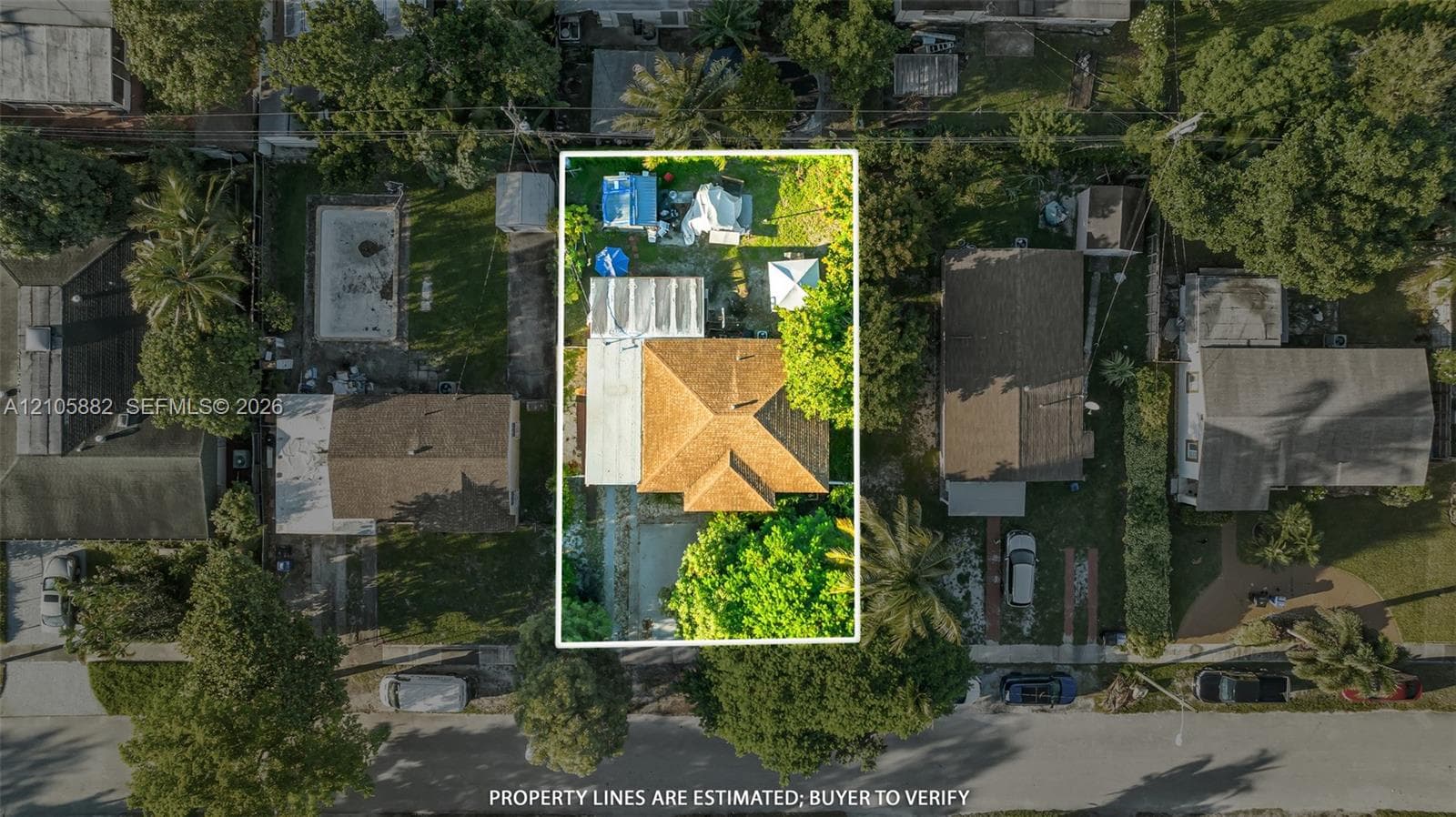 Aerial perspective of a residential lot featuring a hip roof structure, an attached covered patio, a concrete driveway, and established perimeter landscaping