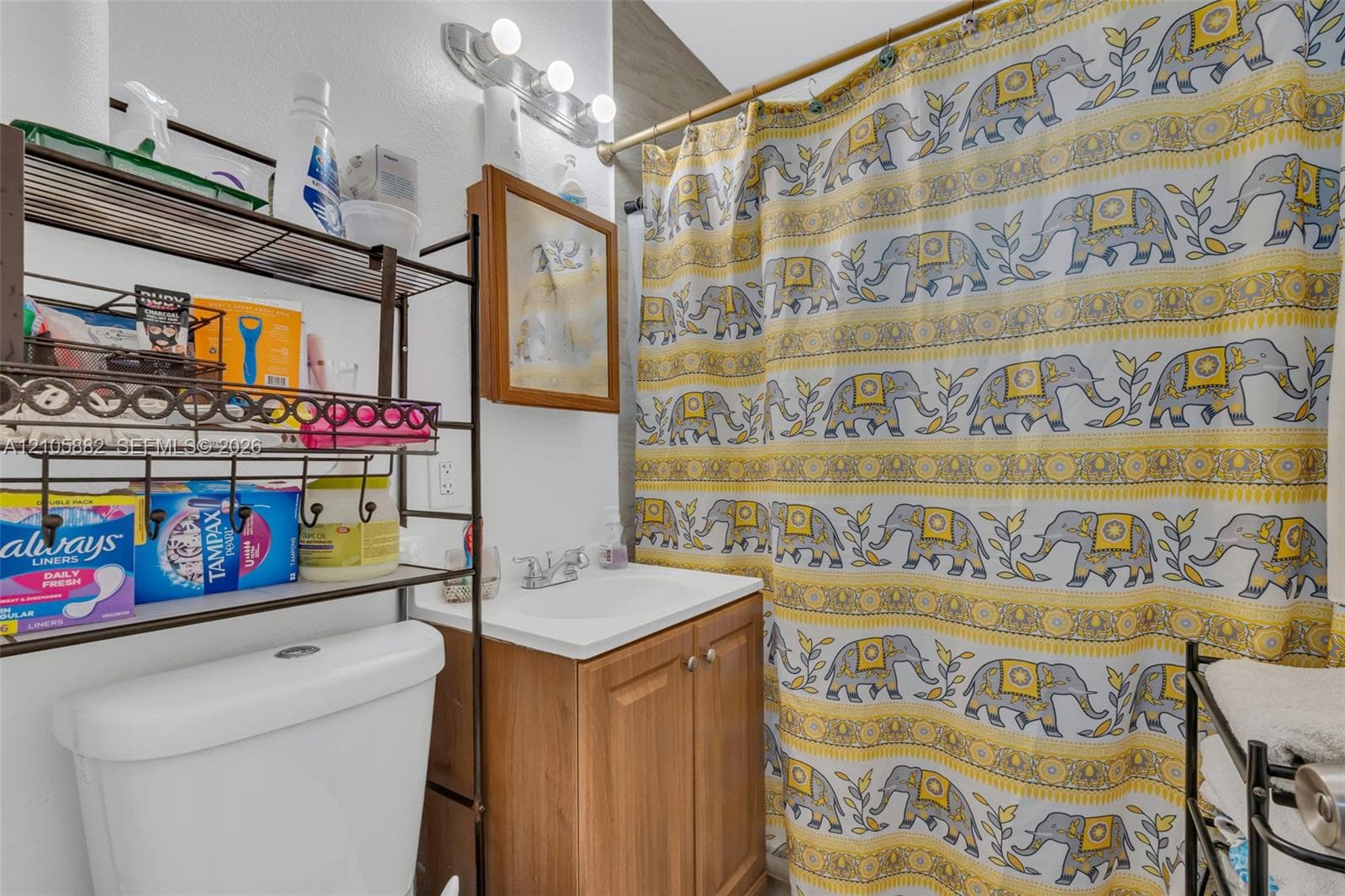 Bathroom featuring a wood-finish vanity with an integrated basin, a three-light vanity fixture, and a tub-shower combination