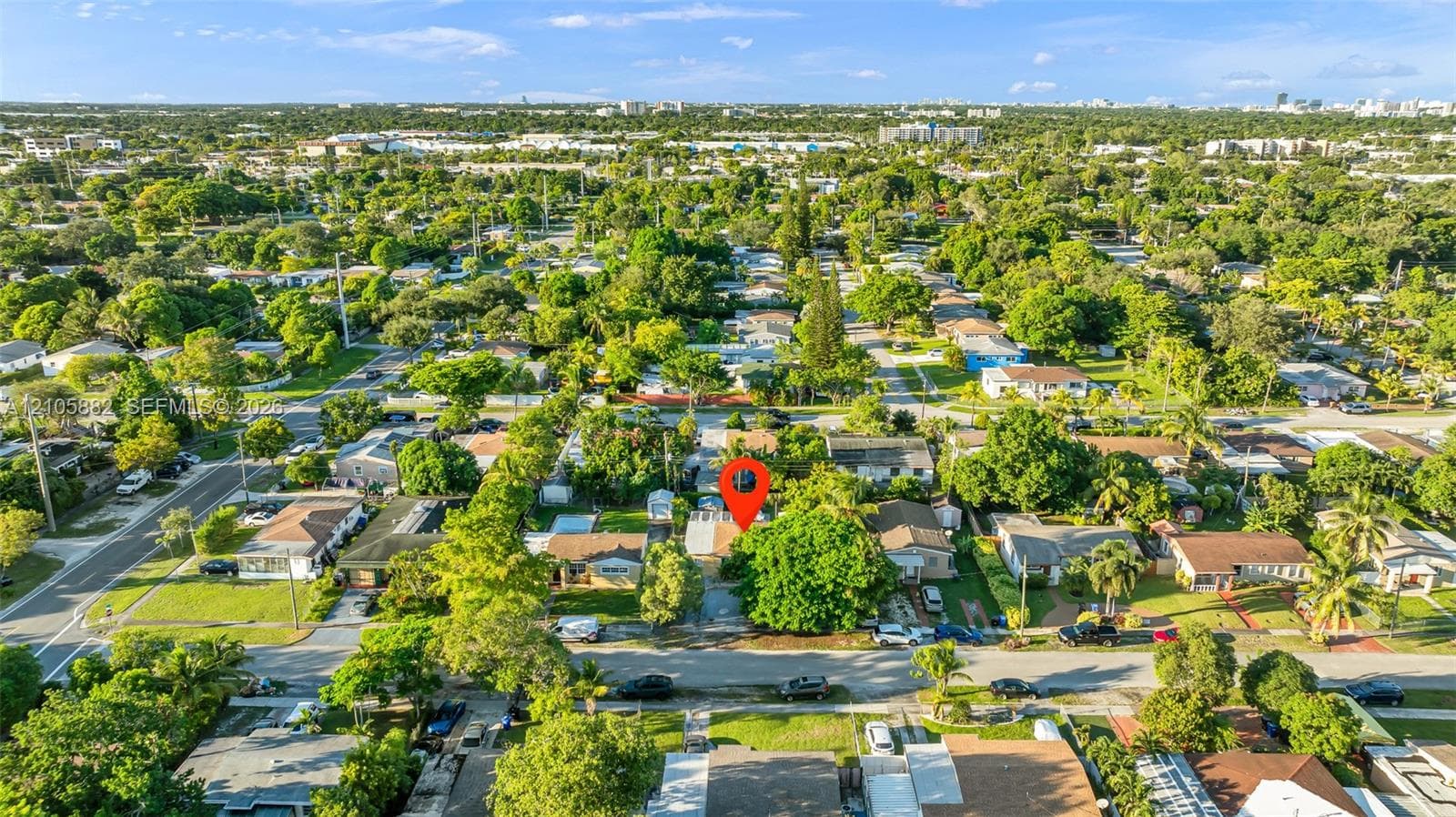 Aerial perspective of a property lot featuring mature landscaping and a paved driveway, situated within a neighborhood of established residential homes