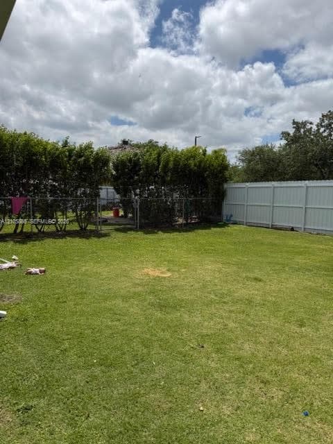 Spacious backyard featuring a manicured lawn, perimeter fencing, and mature shrubbery