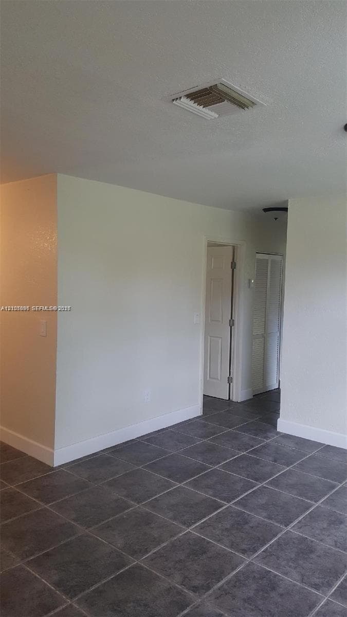 Interior space featuring grey ceramic tile flooring, neutral wall tones, and white interior doors with traditional hardware