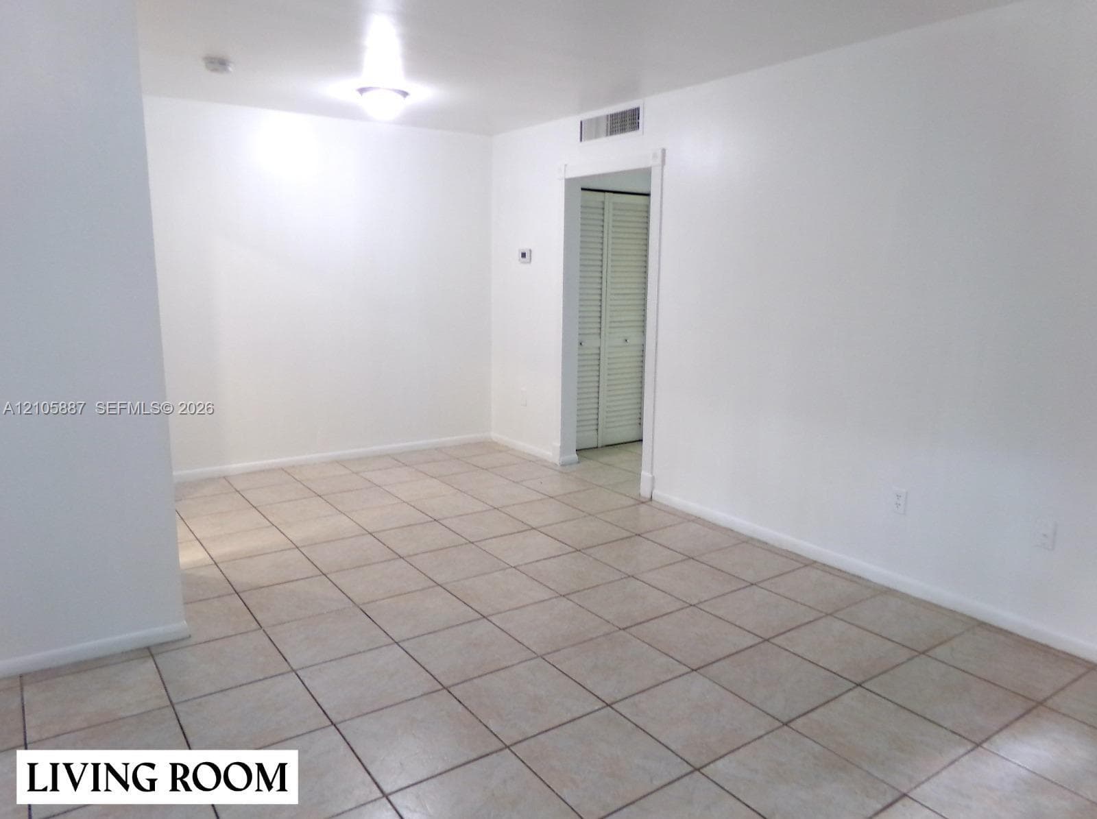 Interior space featuring ceramic tile flooring, neutral walls, and a closet with louvered bifold doors