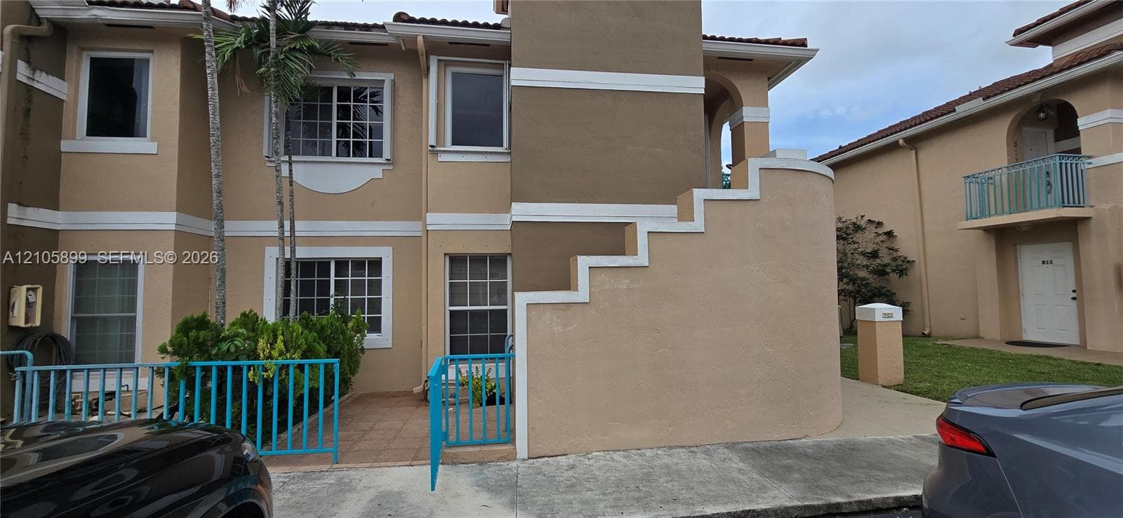 Multi-story exterior featuring a stucco facade with decorative trim, tile-accented patio, and a dedicated fenced entryway