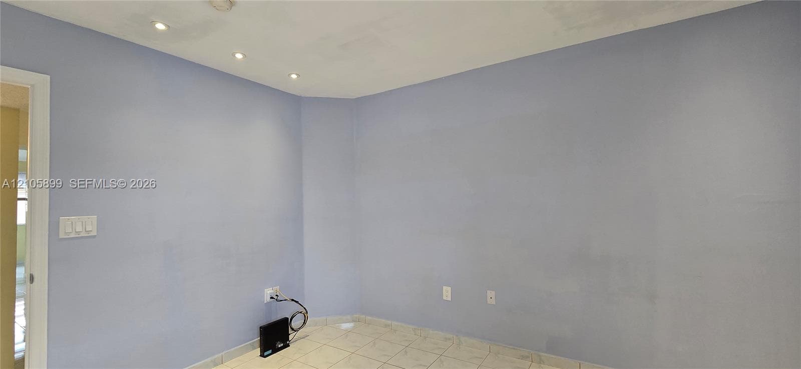 Neutral interior space featuring recessed ceiling lighting, light-toned floor tile, and a doorway entrance
