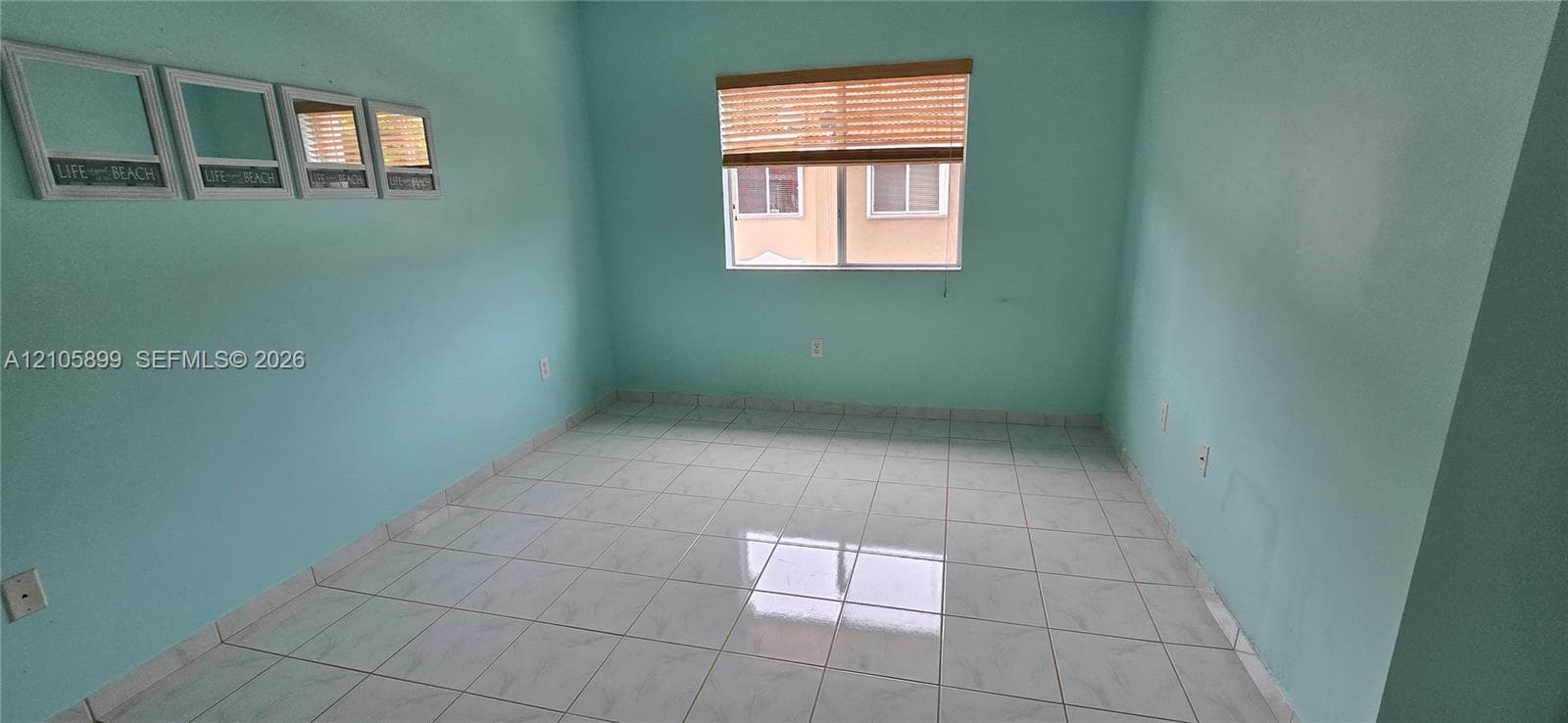 Room featuring square ceramic tile flooring, a large dual-pane window, and woven wood window treatments