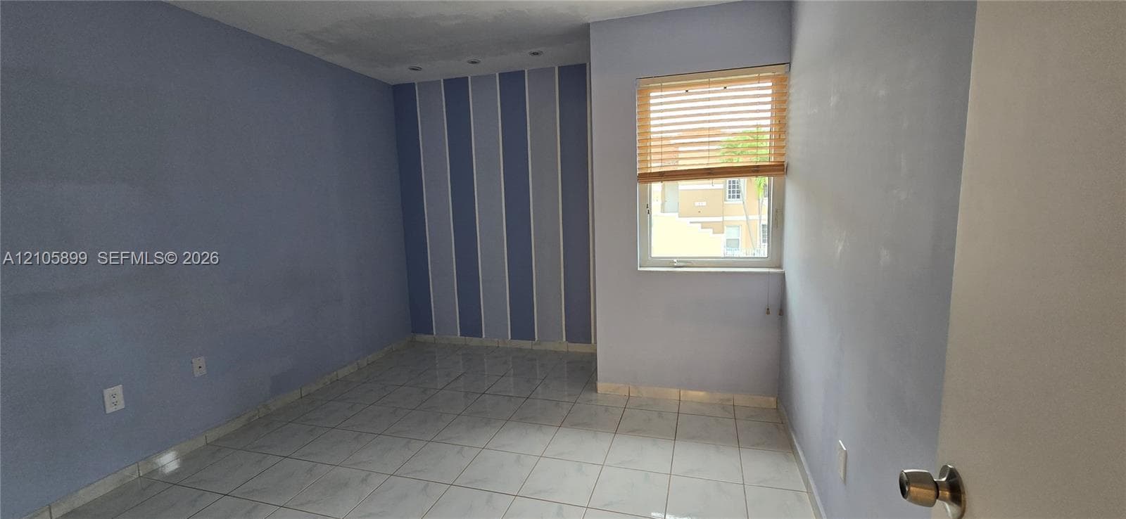 Room featuring large-format ceramic tile flooring, recessed ceiling lighting, and a single-pane window with adjustable slat blinds