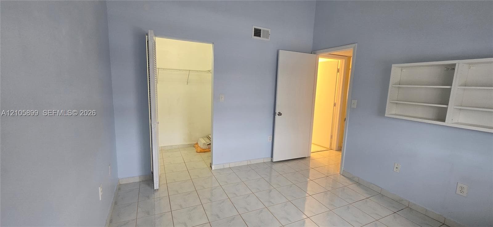 Interior room featuring tile flooring, built-in wall shelving, a reach-in closet with wire rack storage, and a solid-core interior door