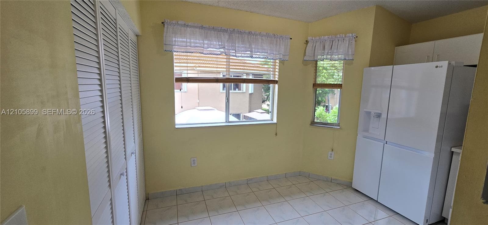Space featuring tile flooring, louvered bi-fold closet doors, and large windows with horizontal blinds