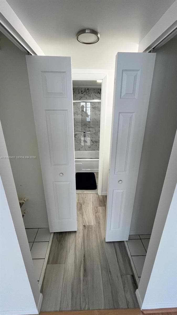 White bi-fold doors, wood-finish flooring, and a flush-mount ceiling fixture