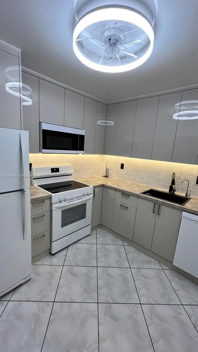 Kitchen featuring high-gloss cabinetry, stone-patterned countertops, a subway tile backsplash with under-cabinet lighting, a built-in microwave, and a flush-mount circular ceiling fixture