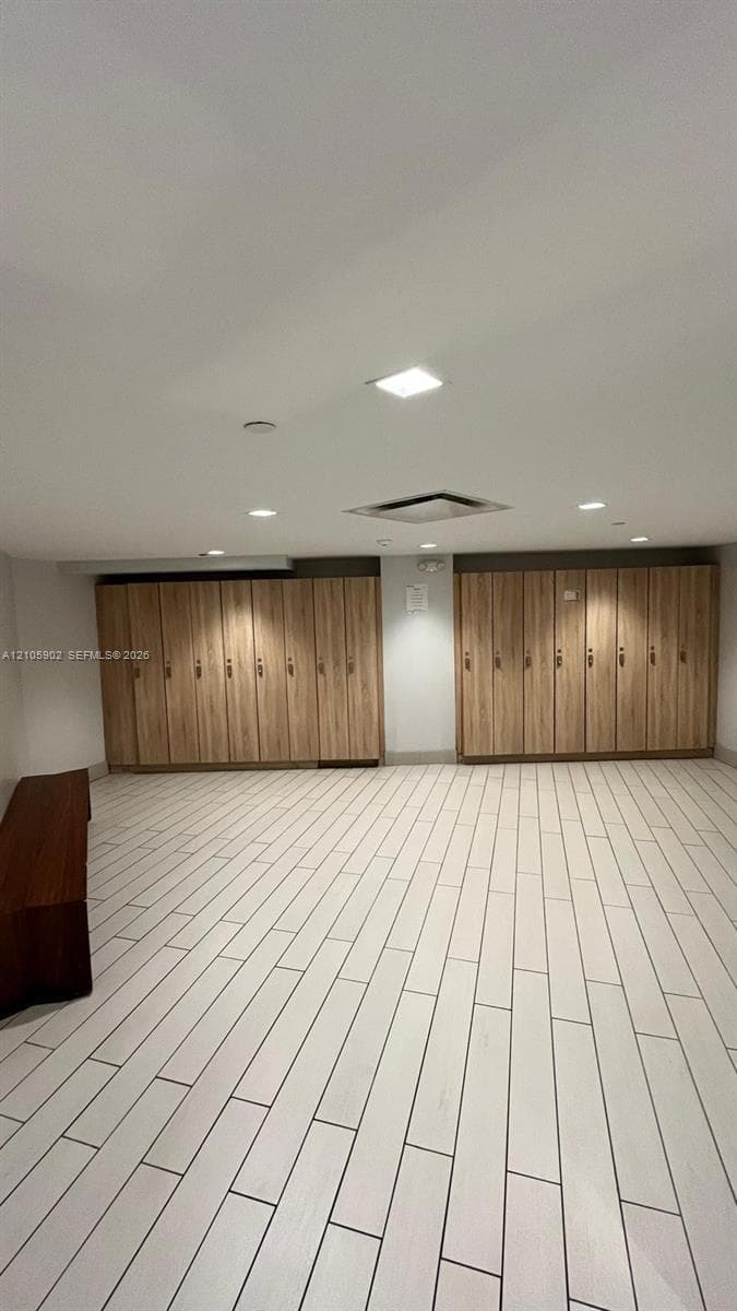 Room featuring extensive wood-finish cabinetry, recessed ceiling lighting, and light-toned ceramic tile flooring