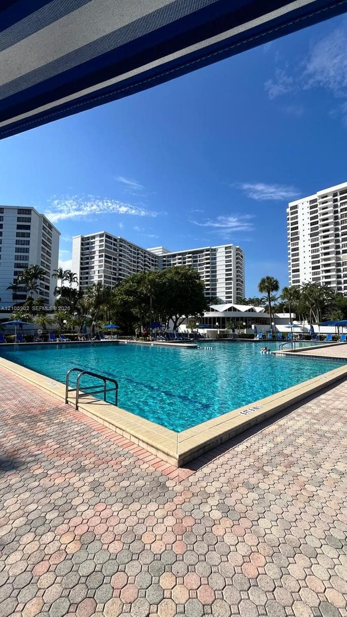 Swimming pool with metal handrails, surrounded by concrete paver decking