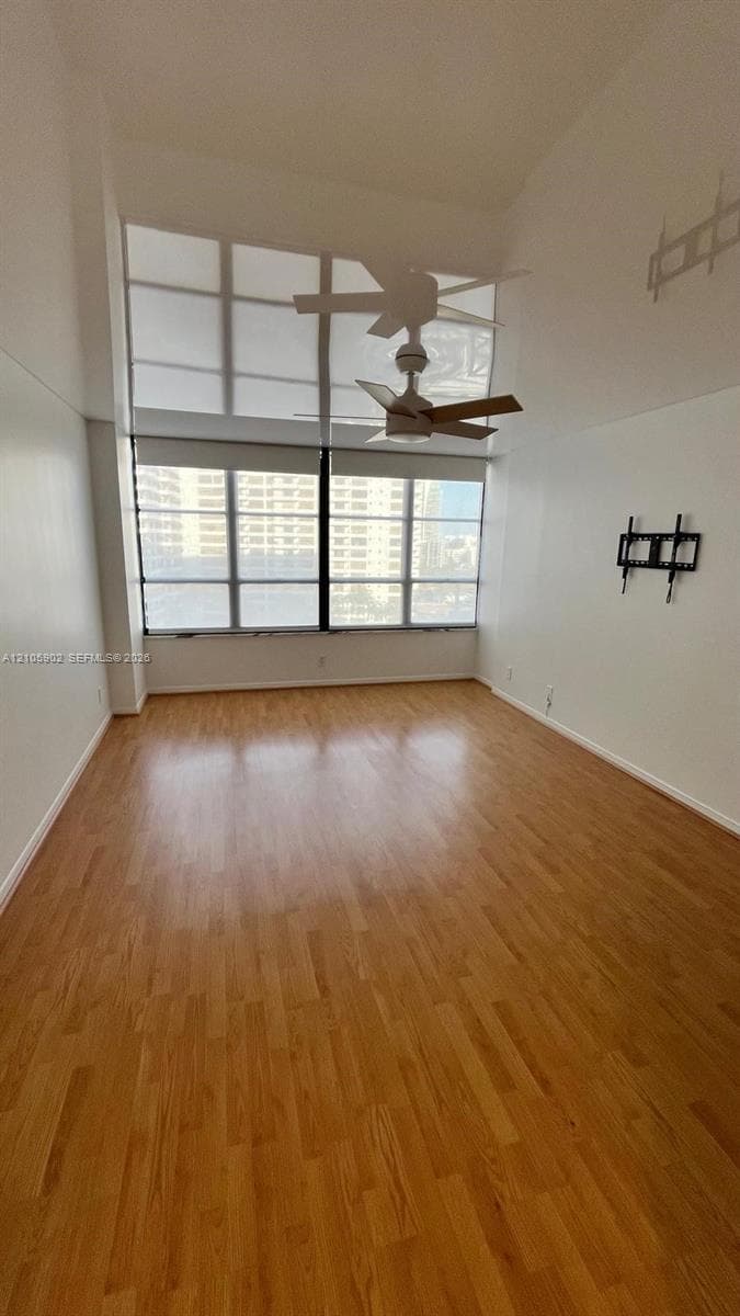 High ceilings, wood-finish flooring, floor-to-ceiling windows, and ceiling fan fixture