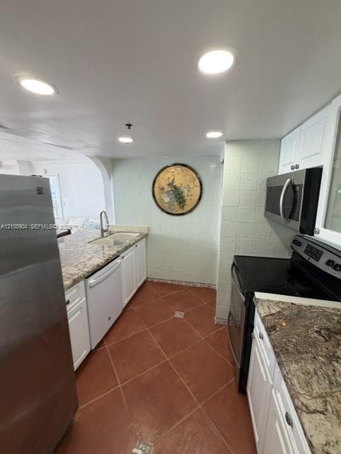 Kitchen featuring white cabinetry, stone-finish countertops, stainless steel appliances, ceramic tile flooring, and recessed lighting