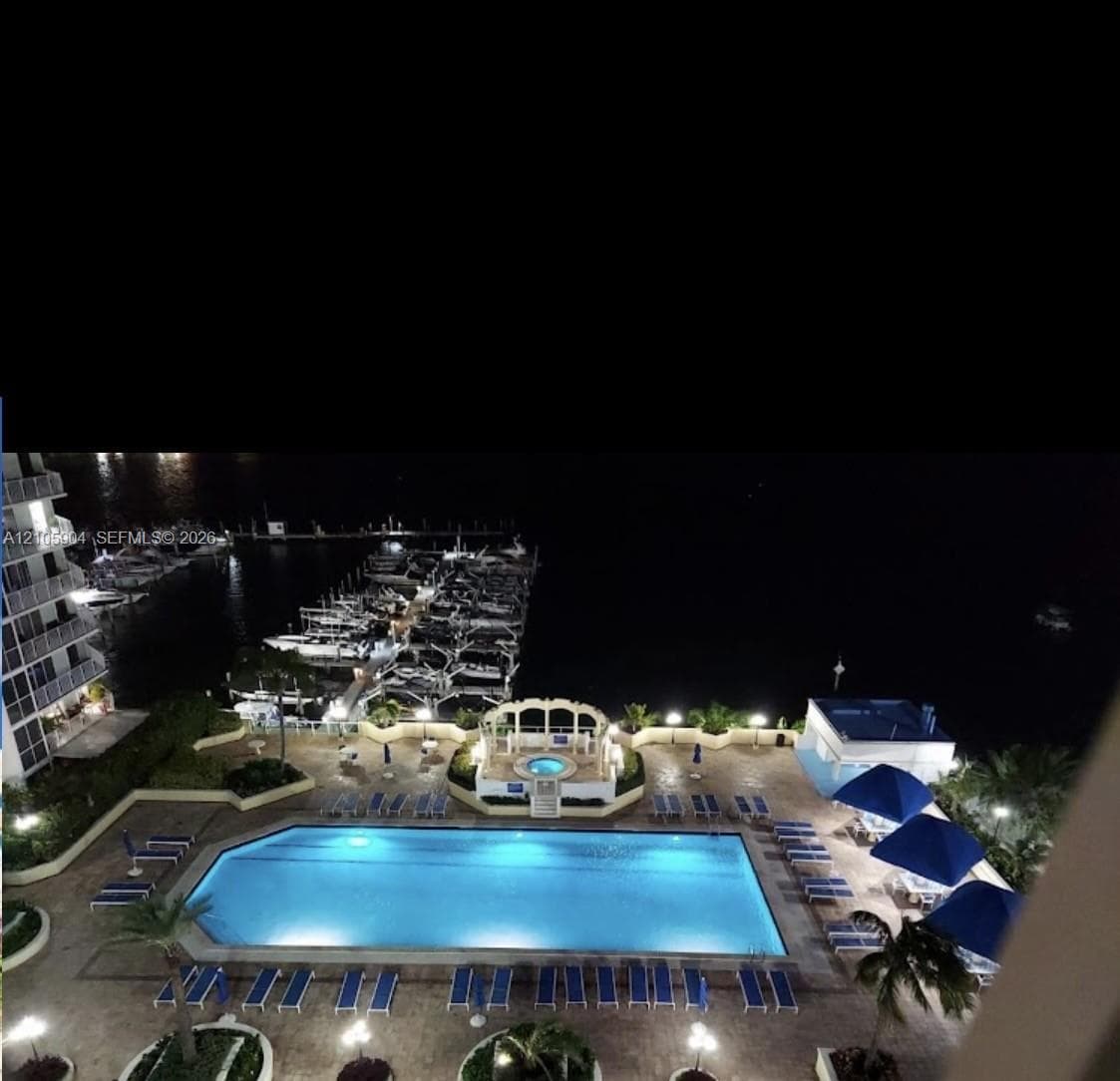 Swimming pool featuring an elevated spa with a decorative arched enclosure, stone-paver patio, and water frontage with private boat slips