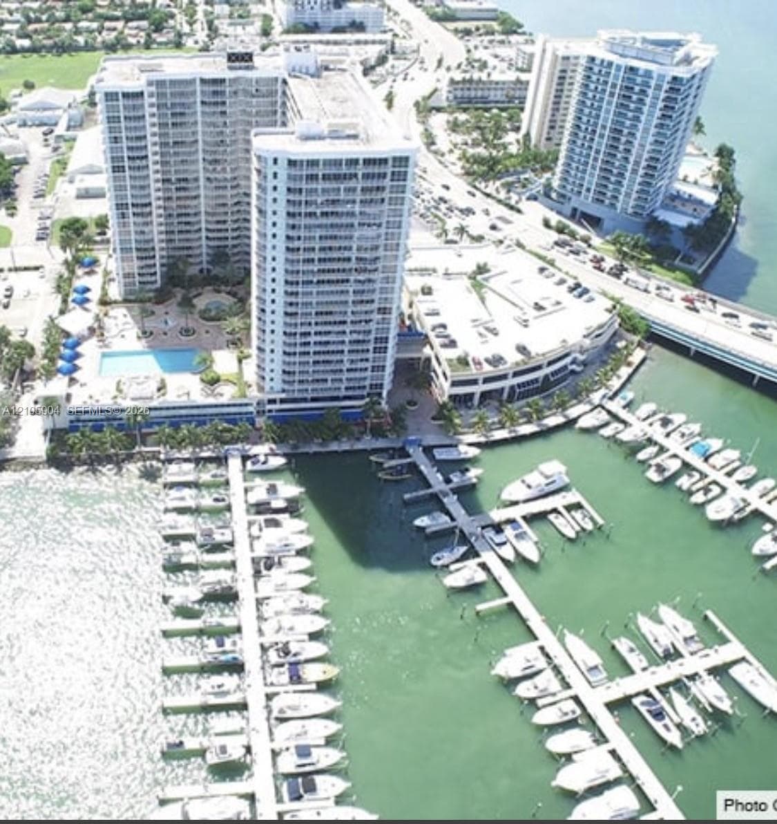 High-rise waterfront property featuring a private marina, swimming pool, landscaped grounds, and attached parking structure