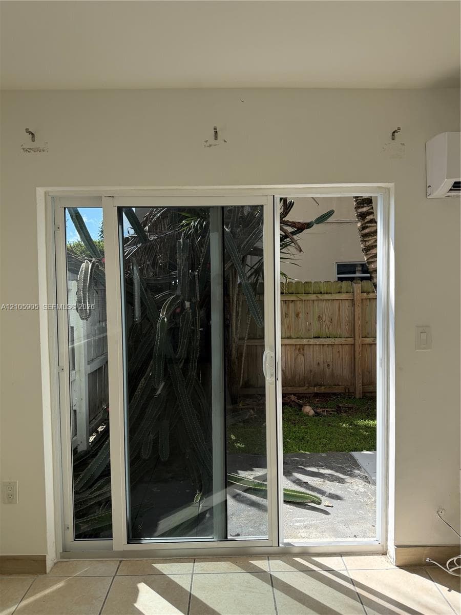 White-frame sliding glass door with large-format floor tile and a wall-mounted climate control unit