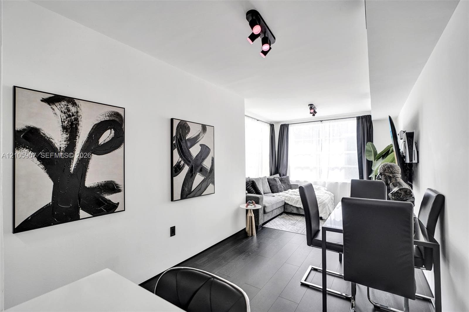 Dark wood-finish flooring, white walls, and multiple adjustable multi-directional track lighting fixtures