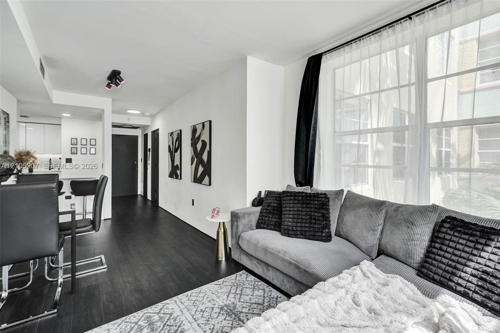 Living area featuring wood-finish flooring, large multi-pane windows, recessed ceiling lighting, and a neutral color palette